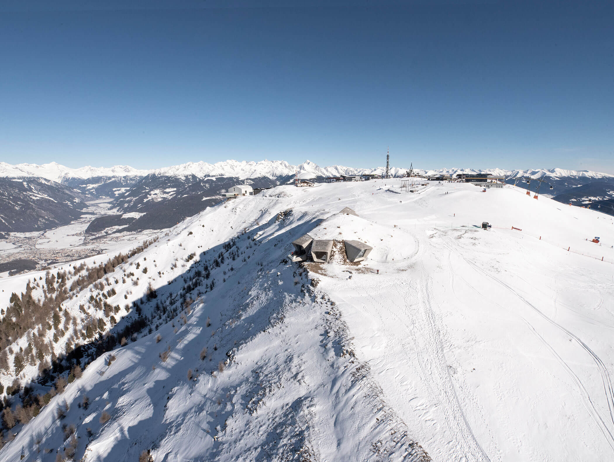 Schneebedeckter Bergrücken mit Gebäuden auf dem Gipfel, umgeben von fernen Bergen unter einem klaren blauen Himmel. - Hotel B&B MyLiving