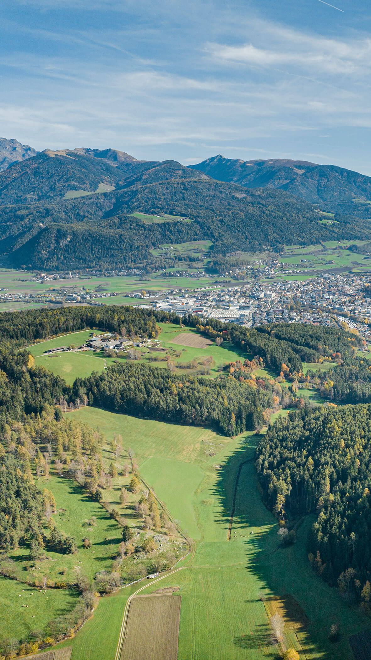 Luftaufnahme von grünen Feldern, Wäldern und einer Stadt mit Bergen im Hintergrund unter einem blauen Himmel. - Hotel B&B MyLiving