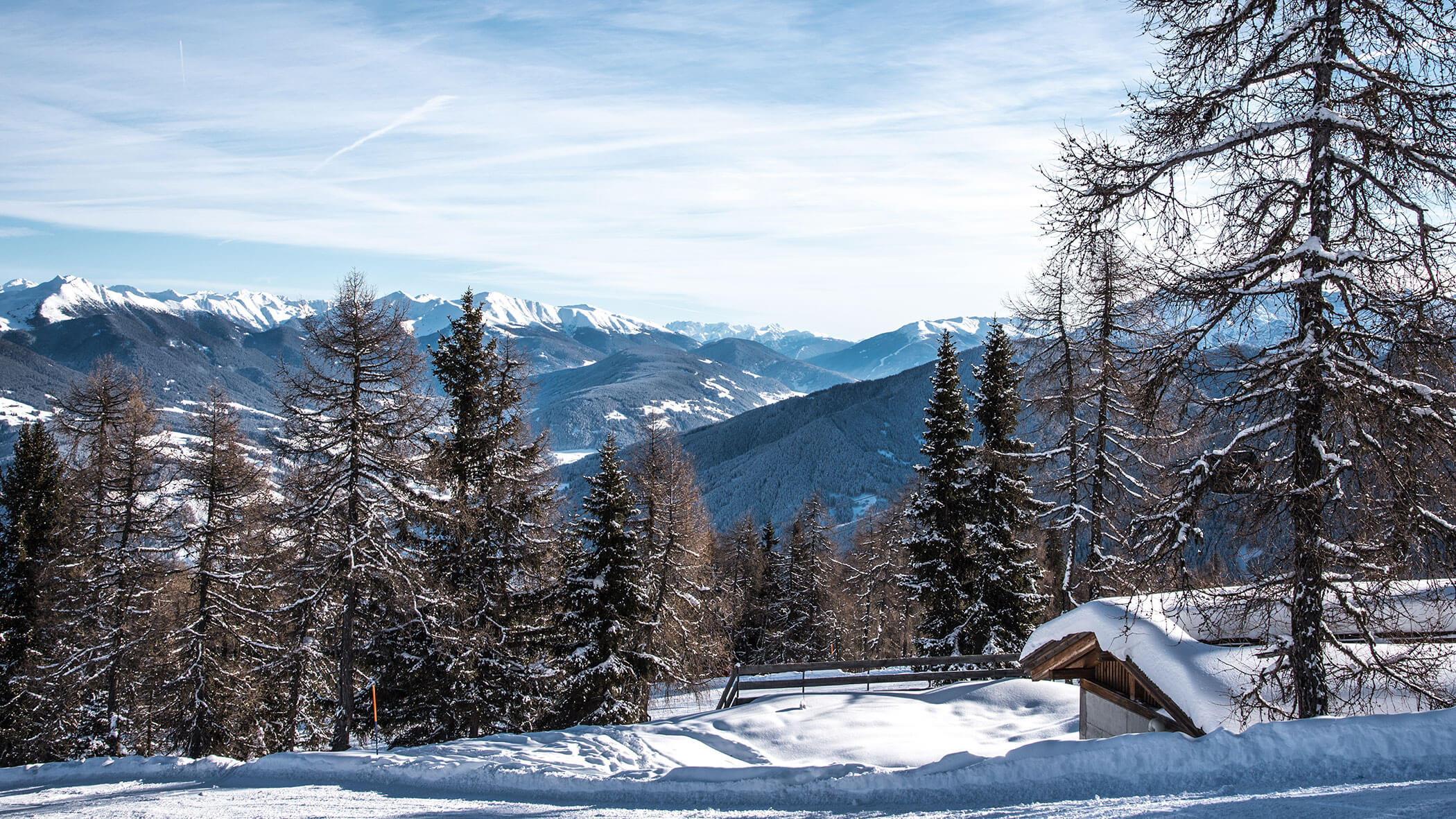 Schneebedeckte Berge und Bäume unter einem klaren blauen Himmel mit einer Holzhütte im Vordergrund. - Hotel B&B MyLiving