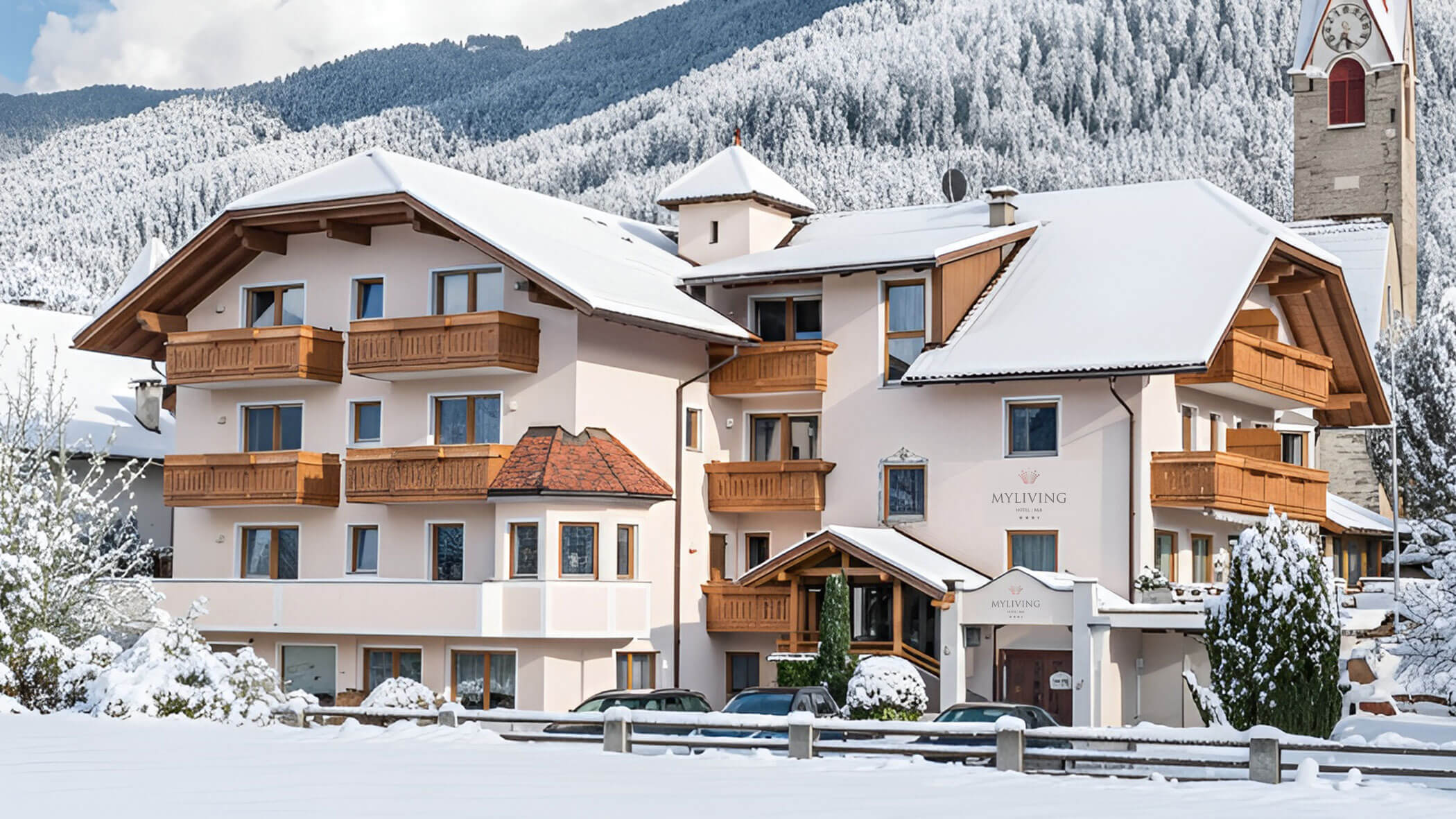 Ein großes Gebäude im alpinen Stil mit schneebedecktem Dach und Balkonen, eingebettet in eine verschneite Berglandschaft. - Hotel B&B MyLiving