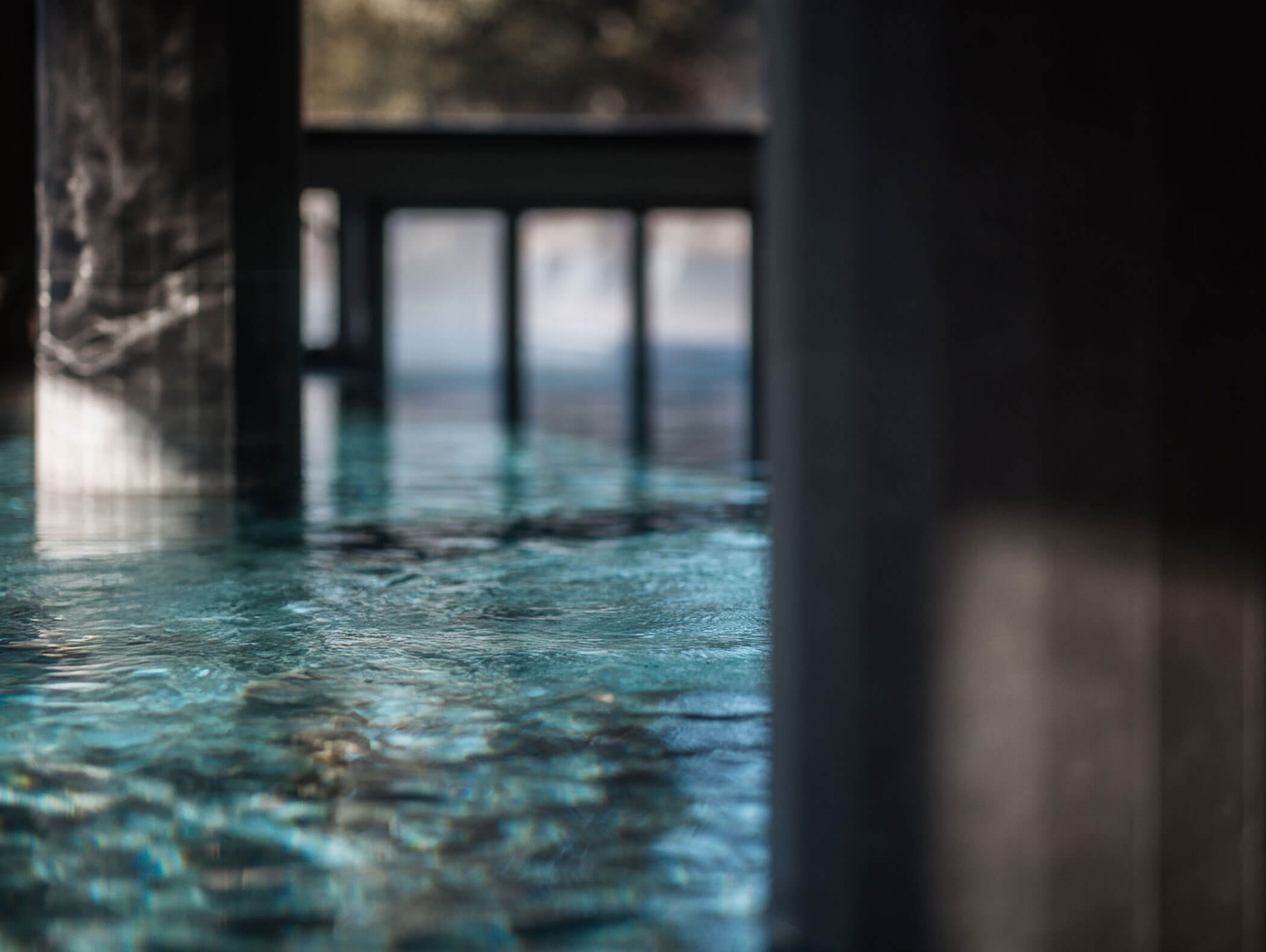 Das Sonnenlicht scheint auf das klare, blaue Wasser unter den Betonsäulen in einem modernen, ruhigen Innenpoolbereich. - Hotel B&B MyLiving