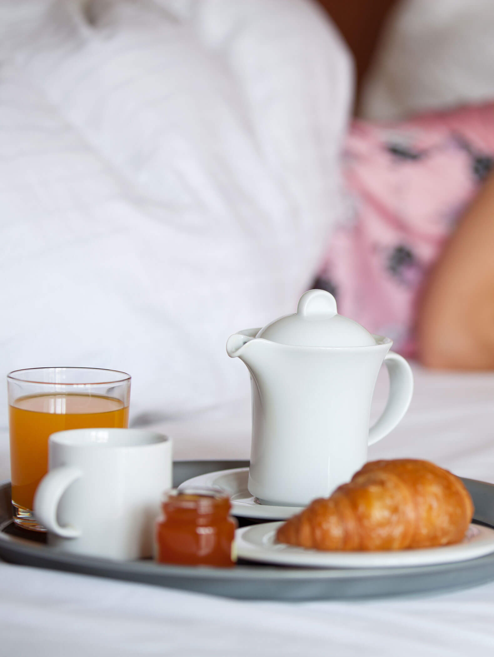 Frühstückstablett mit einem Croissant, einem kleinen Glas Marmelade, Saft, Kaffeetasse und Teekanne auf einem Bett. - Hotel B&B MyLiving