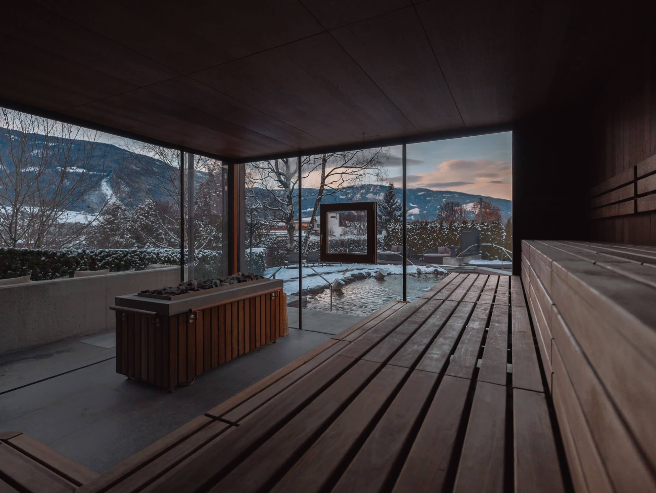 Moderne Innensauna mit Holzbänken, großen Fenstern und Blick auf verschneite Berge bei Sonnenuntergang. - Hotel B&B MyLiving