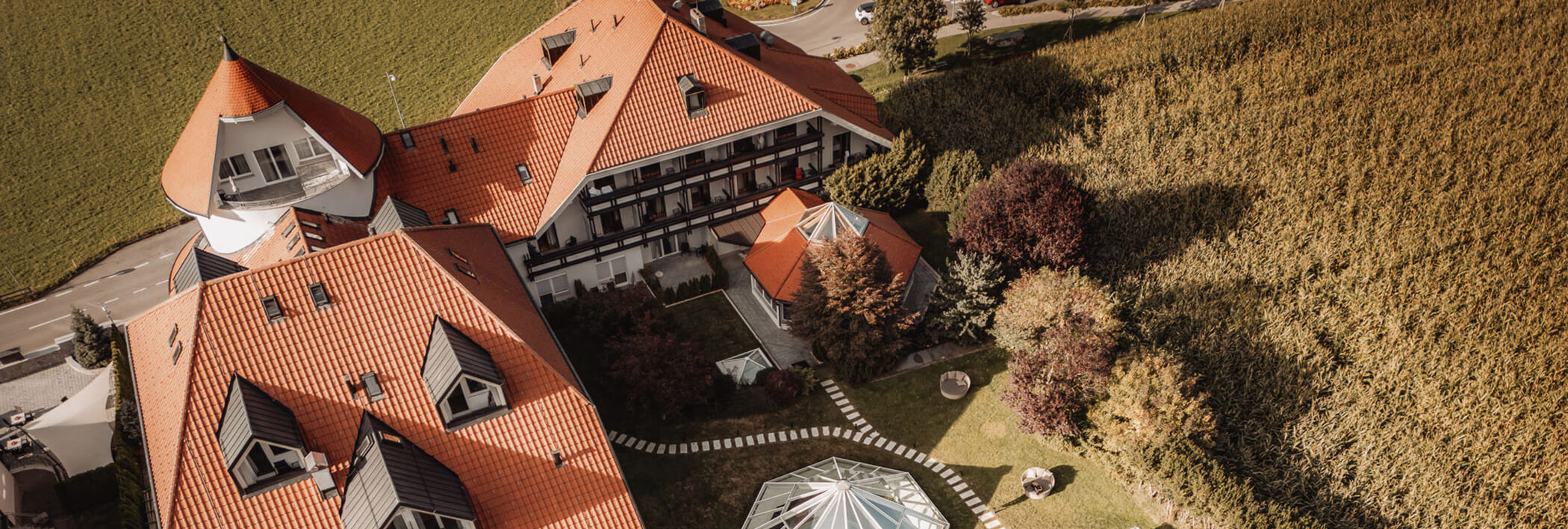 Luftaufnahme eines großen Gebäudes mit roten Dächern neben einem Feld und einem angelegten Garten. - Hotel B&B MyLiving