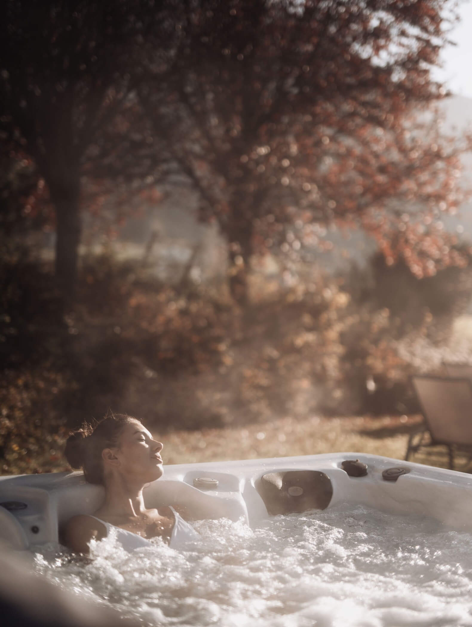 Eine Frau entspannt sich in einem Whirlpool im Freien, umgeben von Herbstbäumen und sanftem Sonnenlicht. - Hotel B&B MyLiving