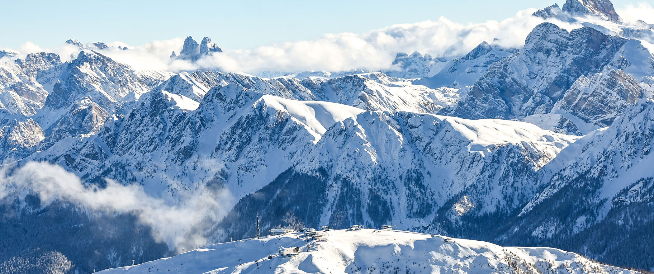 Eine schneebedeckte Bergkette mit zerklüfteten Gipfeln und Wolken, die unter einem strahlenden Himmel zwischen den Gipfeln treiben. - Hotel B&B MyLiving