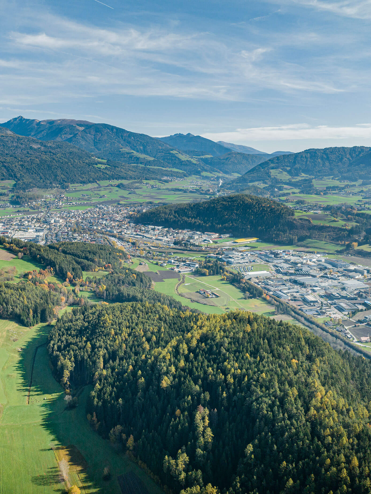 Luftaufnahme einer Stadt, umgeben von grünen Wäldern, Feldern und Bergen unter blauem Himmel. - Hotel B&B MyLiving